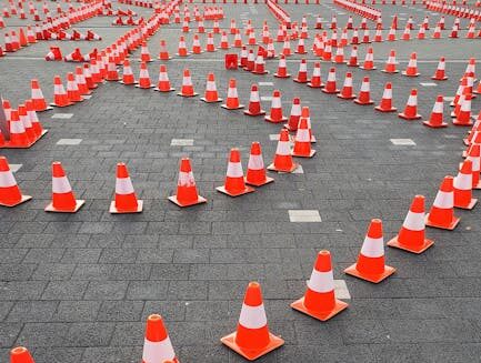 Aerial view of traffic cones arranged on a paved surface, forming a complex pattern.